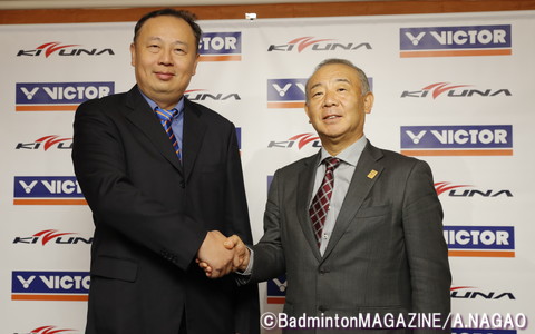 檀上で握手を交わすVICTORスポーツの陳社長（左）とKIZUNAジャパンの阿部社長